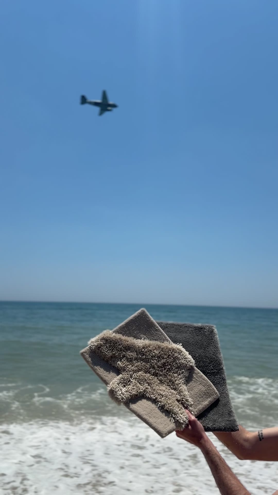 A regenerated nylon rug sample held against the sea, showing sustainable yacht carpeting material.